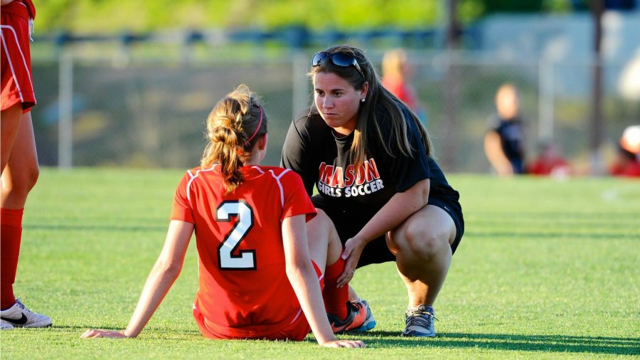 A soccer coach talking to her player on the field.