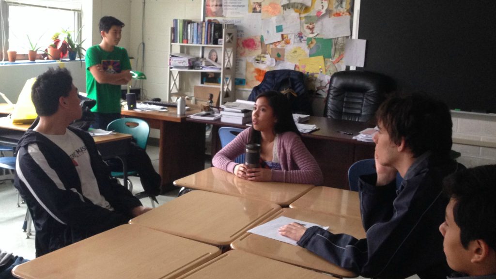 Students sit at a table during a discussion.