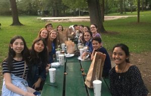 A group of students eating at a picnic table at a park.