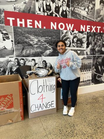 Sophomore Joyce Tadesse Kassa poses next to her clothing drive, located in the lobby of Meridian. (Photo courtesy of Elbetel Kiros)