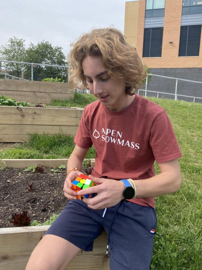 Dimock is solving a Rubik’s Cube outside, a place where he spends a majority of his time. Dimock is utilizing an algorithm where he is attempting to accumulate a T-formation with the white-faced cubes. (Photo by Joyce Tadesse Kassa)