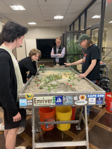 Sophomores Adam Belouad and Grace Calabrese gather around a watershed model created from microplastic, listening to NoVa staff discuss Virginia’s waterways. (Photo by Vedika Thapliya)