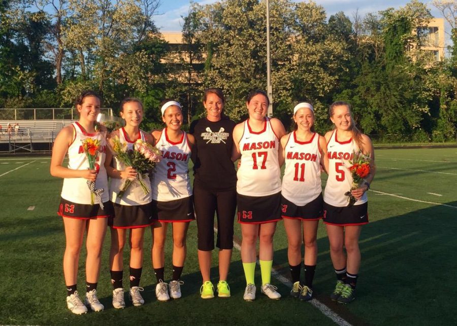 Lacrosse players and coach holding flowers on Mason field
