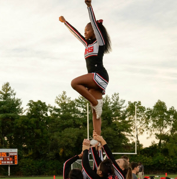 Cheerleader is lifted in the air by her teammates