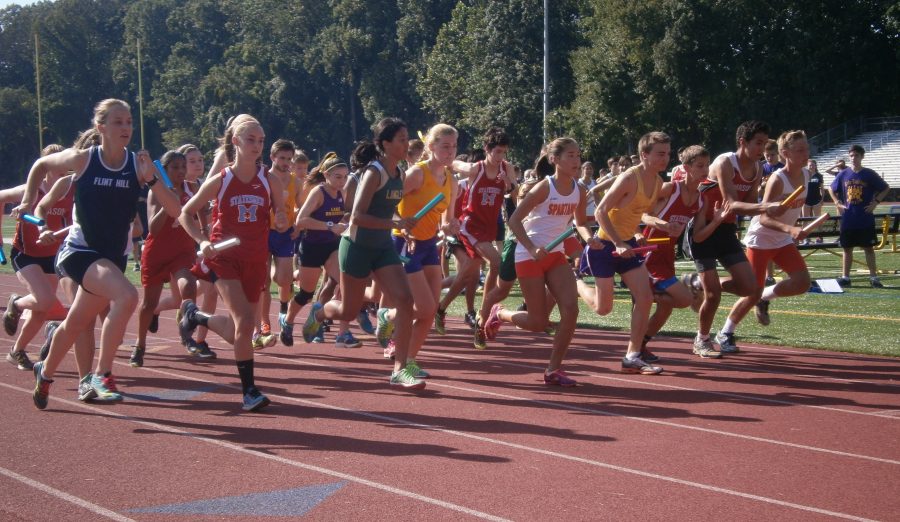 A group of runners run on a track.