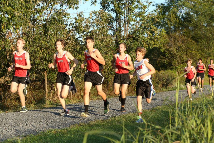Mason cross country boys from left to right sophomore Griffin Warner, junior Conway Teehan Dodge, sophomore Daniel Mineo, sophomore Samuel Updike, and eighth grader Drew Langford race to the finish line along the rocky path during a meet. (Photo courtesy of Lifetouch Photography)