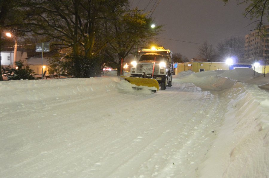 A plow coming down a snowy street.
