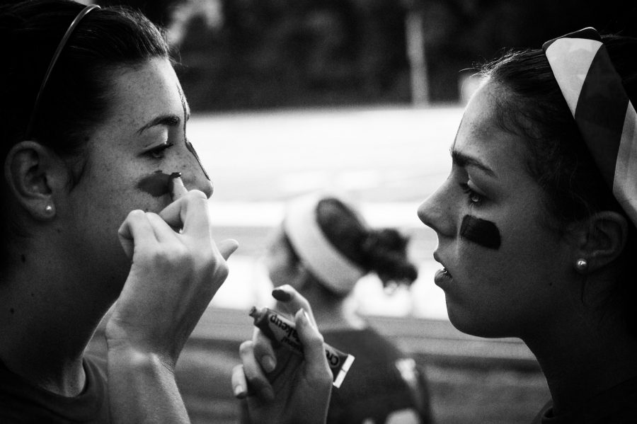 A junior girl putting face paint on a teammate