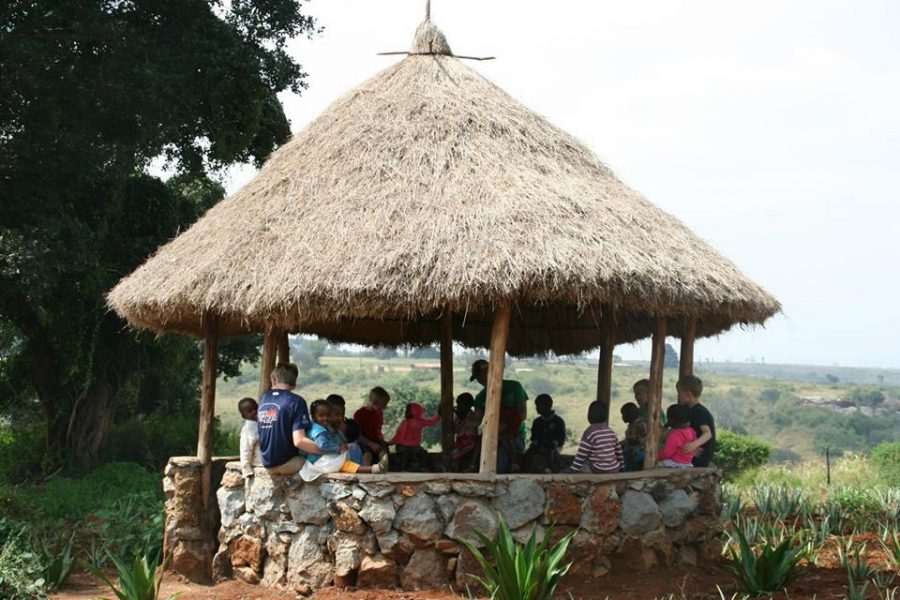 A gazebo made of straw and stone filled with children and the Gaskins family.