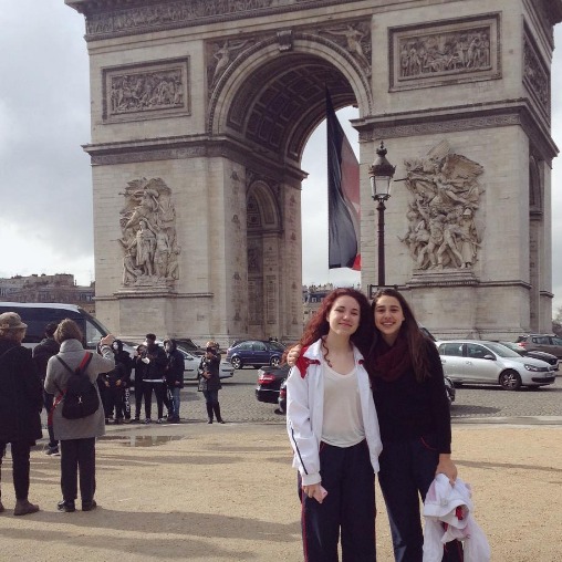 Two girls pose by a French monument.