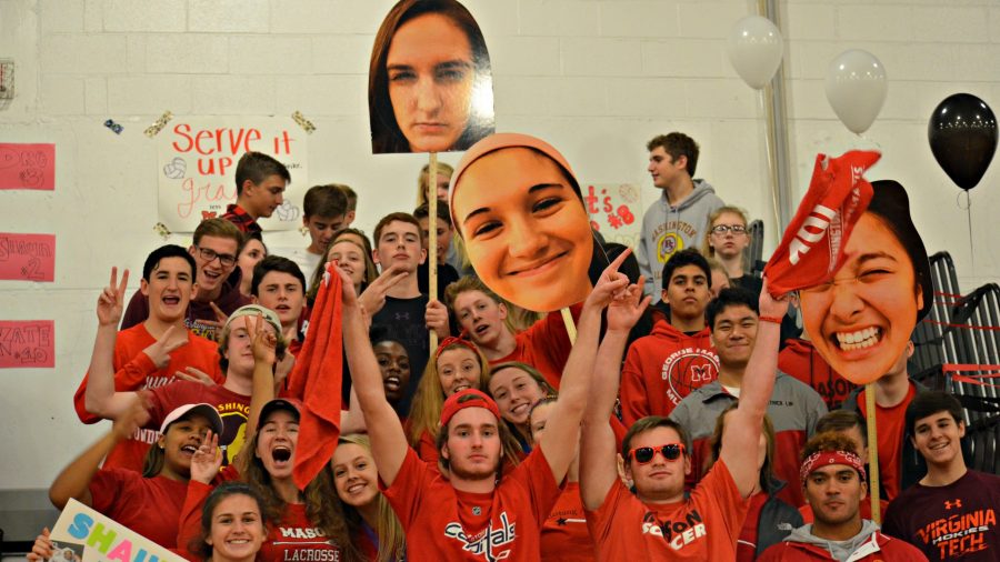 The student section, known as the boom squad, holds up large posters of the seniors heads.