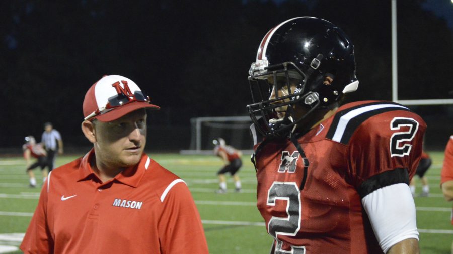 A coach and football player talking on the sidelines.