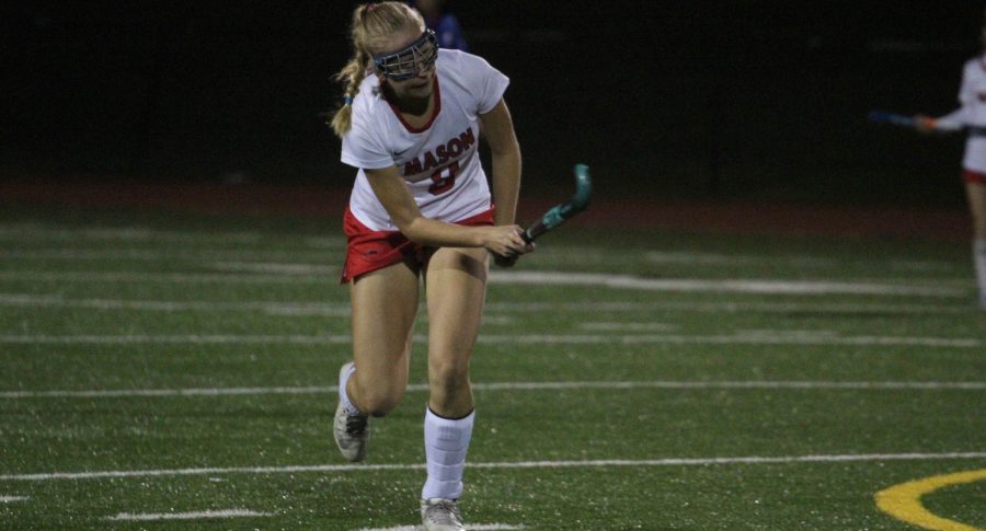 A field hockey player running down the field.