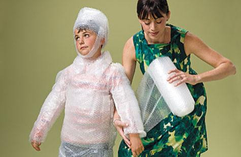 A mother wraps her son in bubble wrap.