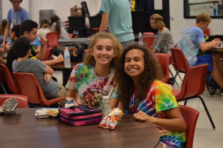 two girls smile while sitting at a table