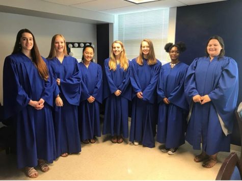Seven girls stand in blue robes in a mock Supreme Court.