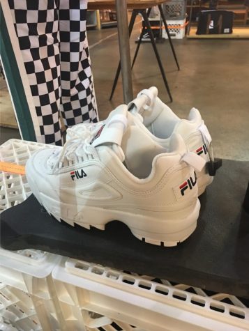 Large white sneakers are on a display in a store.