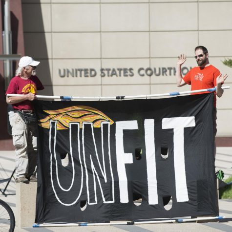 Two protestors hold a sign in Minneapolis, Minnesota that reads, “Unfit” with the outline of President Trump’s [in]famous hair drawn on the poster.