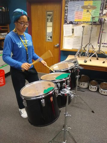 Girl plays drums in practice room.