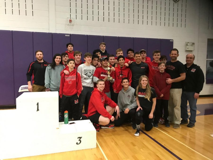 a group of wrestlers and coaches pose with a trophy.
