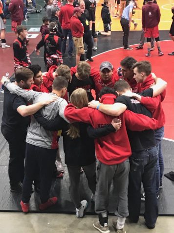 A group of athletes and coaches huddle together.