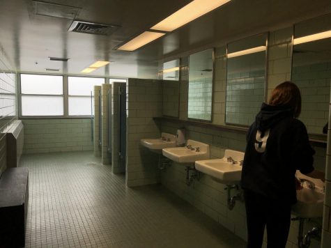 Student washing hands in bathroom.