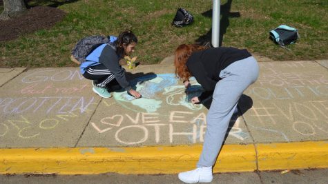Girls writing with chalk on the school sidewalk.