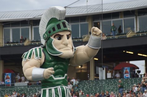 Sparty stands and flexes at a football game