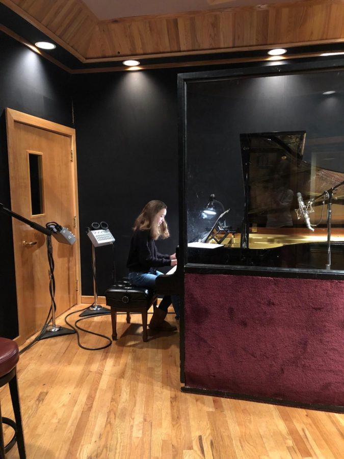 Meghan sits at a piano in the studio practicing her music.