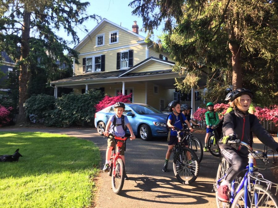 Students ride their bikes down a driveway.