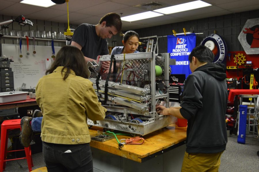 Captains Sophia Heartney (left) and Sarah Fong (middle) work on the robot in the MakerSpace. (Photo by Stella Turner)