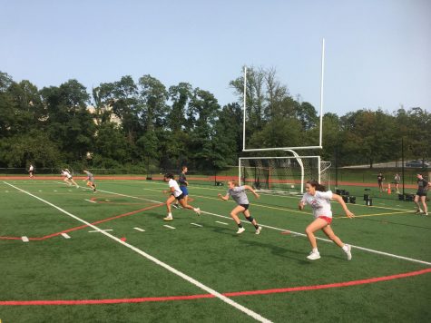 Girls' basketball players run sprints up and down the turf field