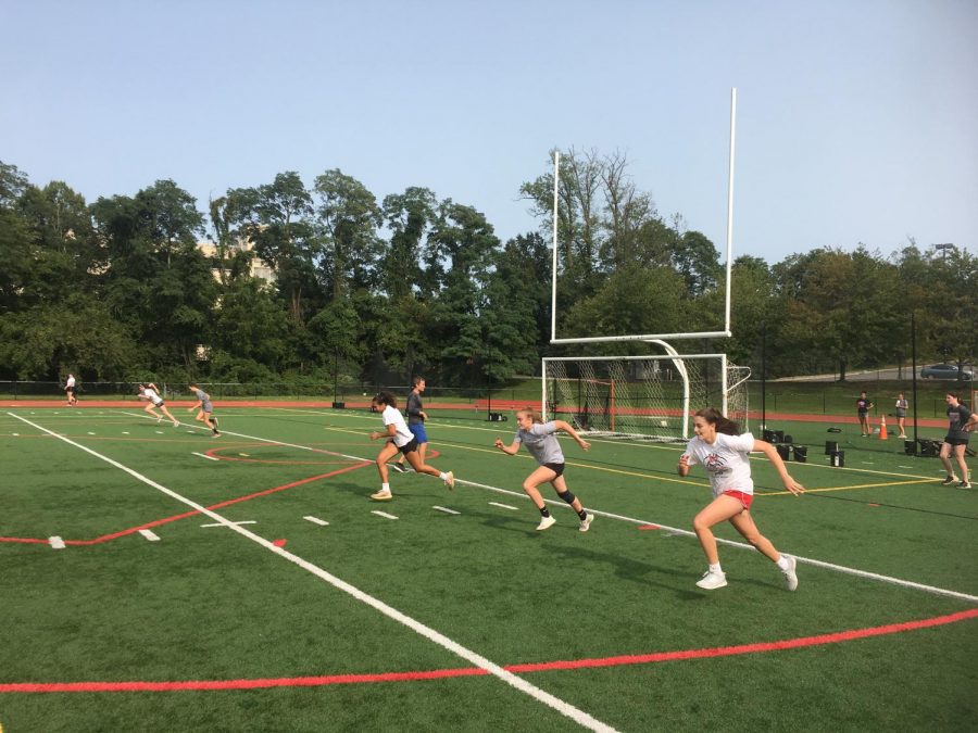 Girls basketball players run sprints up and down the turf field