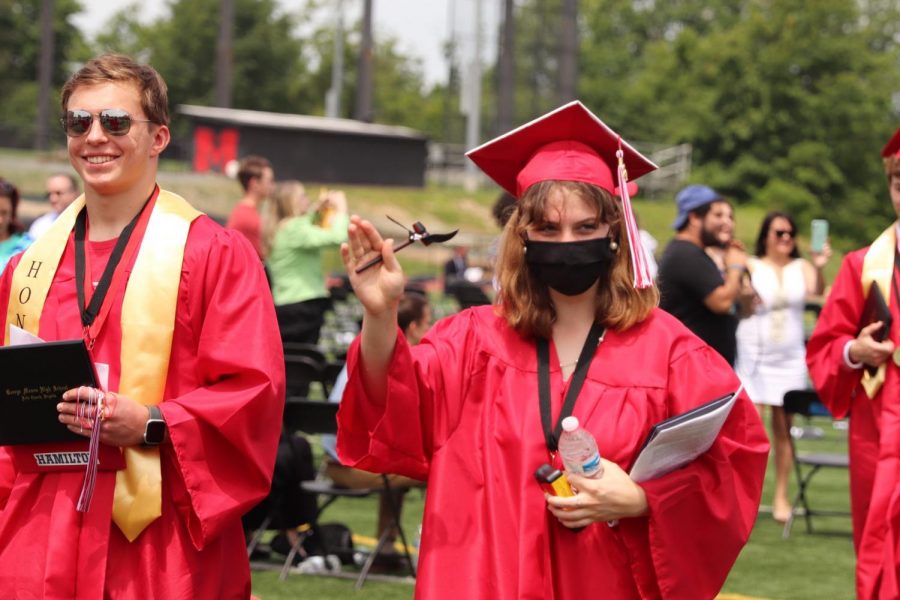 Graduates Bobby Asel and Izzy Anderson exit the ceremony after ringing the graduation bell with individual mallets.
