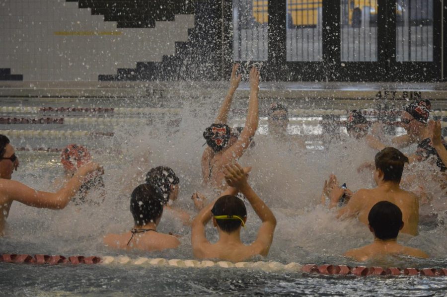 Mustang swimmers splash the water during a team cheer.