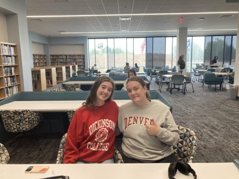 Greta Hermann and Emma Tice-Kepner sit in college sweatshirts.