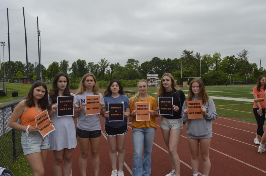 Juniors Erin Tarpgaard, Katie Rice, Anna Dickson, Hope Kleinberg, Hanna Hall, Clara Kasik, and Mia Mayer hold signs that say enough is enough and protect children, not guns. (Photo by Isabel Costa)