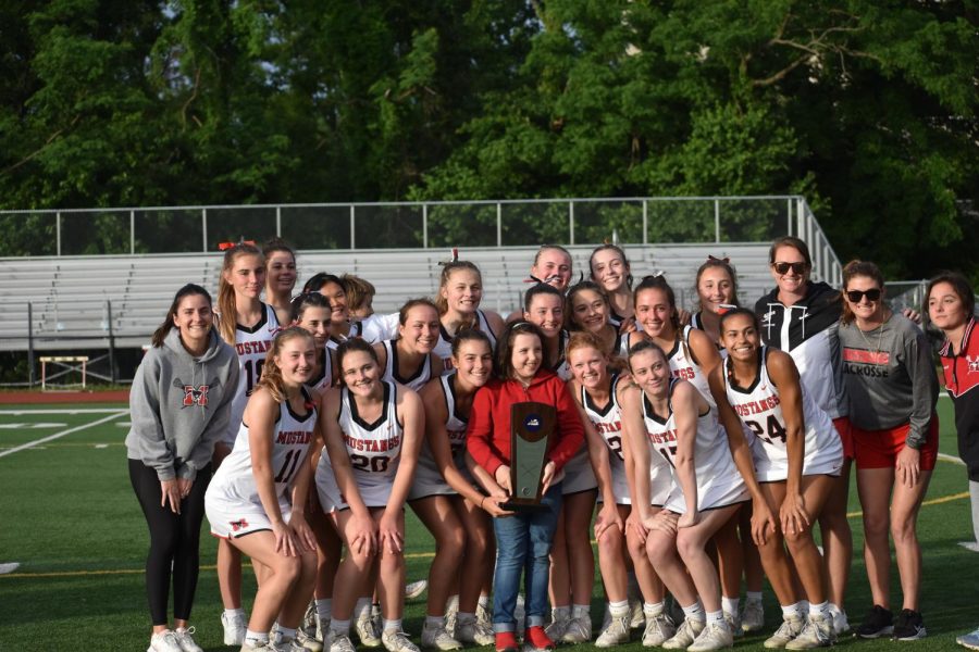 Girls lacrosse takes a team photo with the trophy. (Photo by Molly Moore)