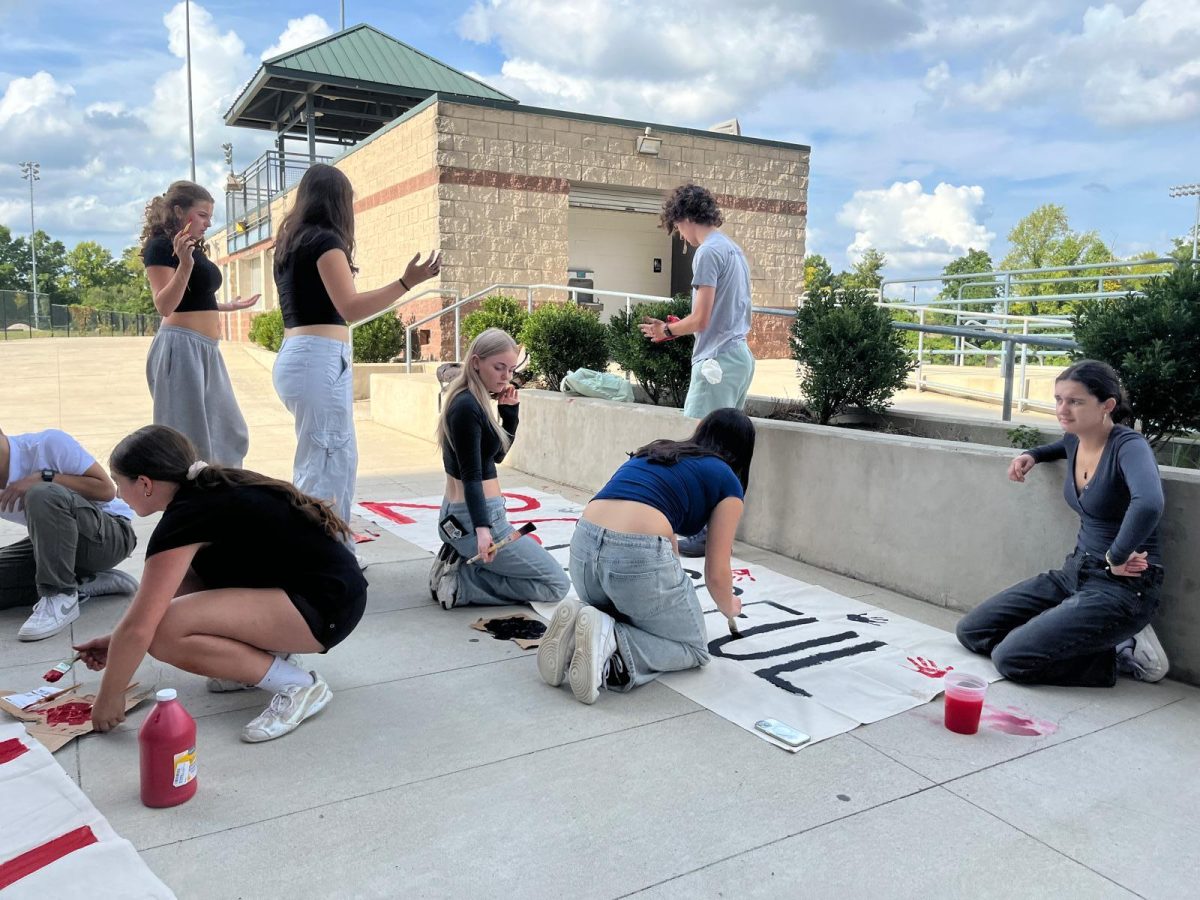 The 2027 SCA fills their banner with red and black handprints to add detail to their poster. In the photo from left to right: Welby Smith, Sanaa Washiko, Claire Hartenstien. (Photo by Faaz Tahir)