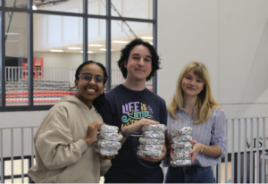 Hand to Hunger founders, Elbetel Kiros, Adam Belouad, and Grace Calabrese hold stacked sandwiches after a meal packing event. (Photo courtesy of Adam Belouad)