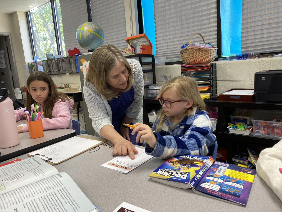 Ms. Schimmoller assists a third grade student with classwork. (Photo courtesy of Chrissy Henderson)