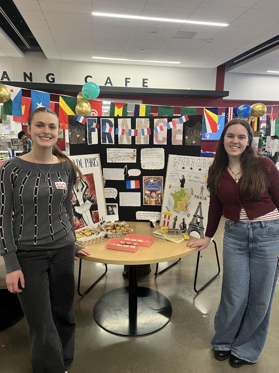  Sophomore Jane Riblett and senior Victoria Olaru pose in front of their booth commemorating the culture and food of France. (Photo via Instagram @meridianinternationalclub)
