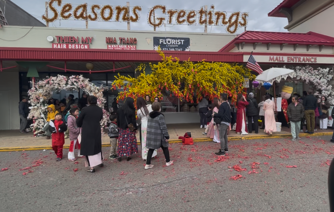 Festivalgoers take photos underneath blossom arches as red firecracker confetti lines the curb. (Photo by Grace Simpson)