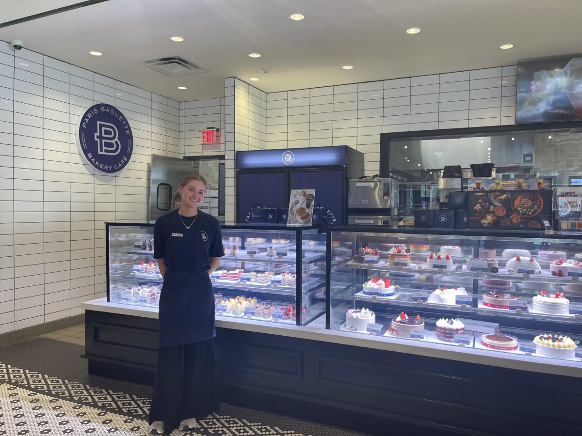 Paris Baguette Cafe staff member Ashley poses in front of the cake display. (Photo via Grace Simpson)