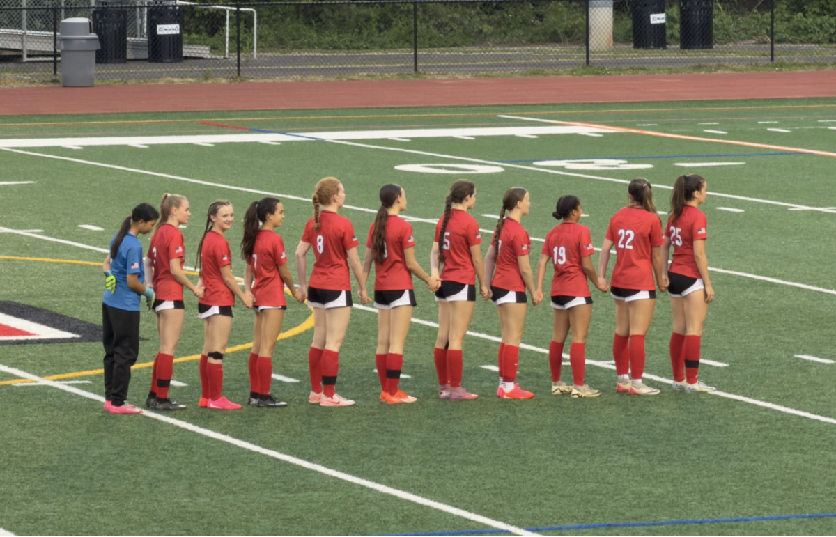 The Mustangs stand facing the flag for the national anthem. (Photo by Dinos Simcox)
